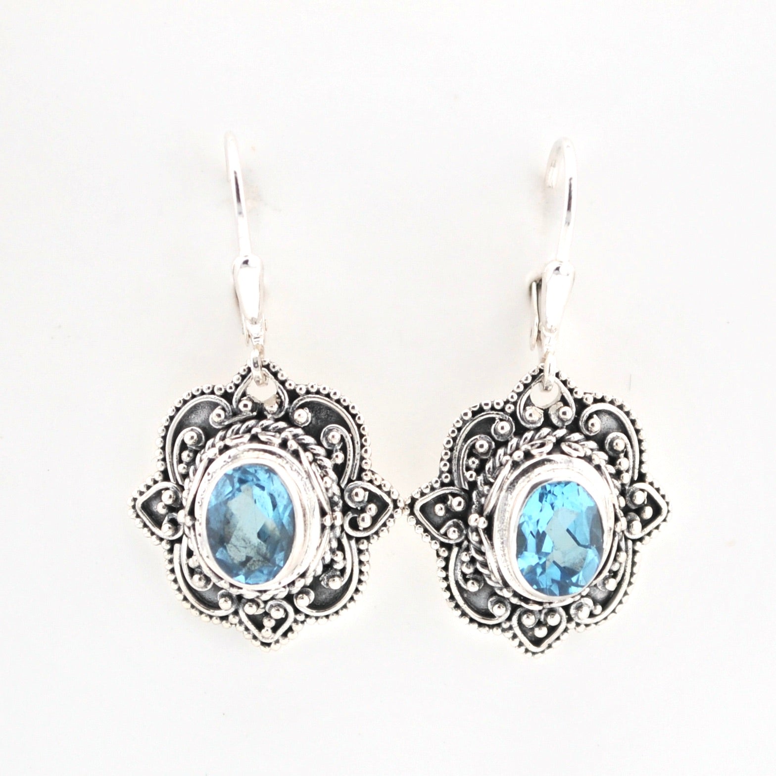 Pair of silver earrings with blue gemstones on a white background