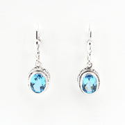 Pair of silver earrings with blue gemstones on a white background