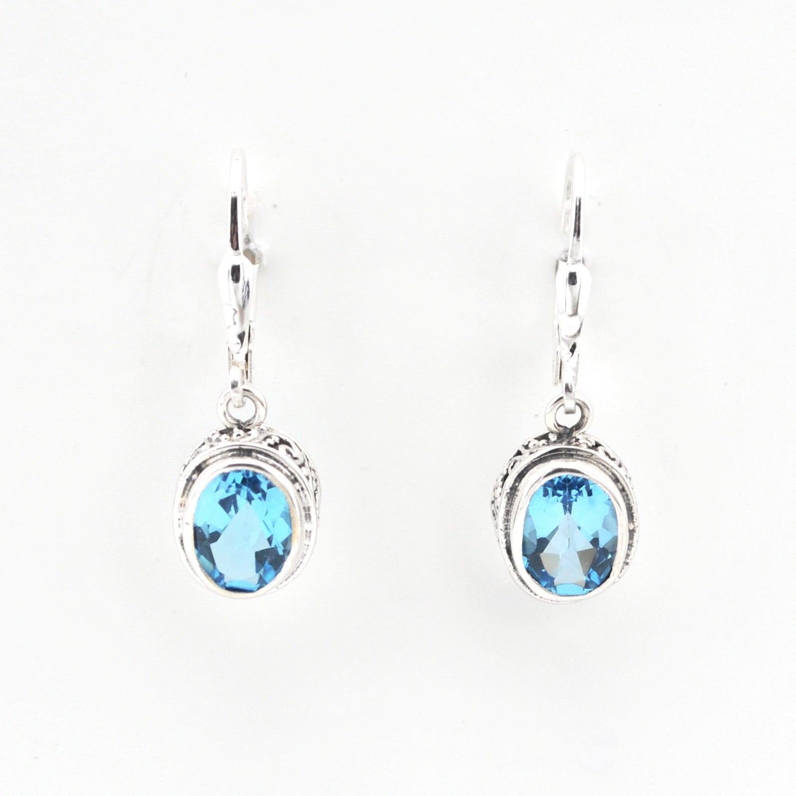 Pair of silver earrings with blue gemstones on a white background