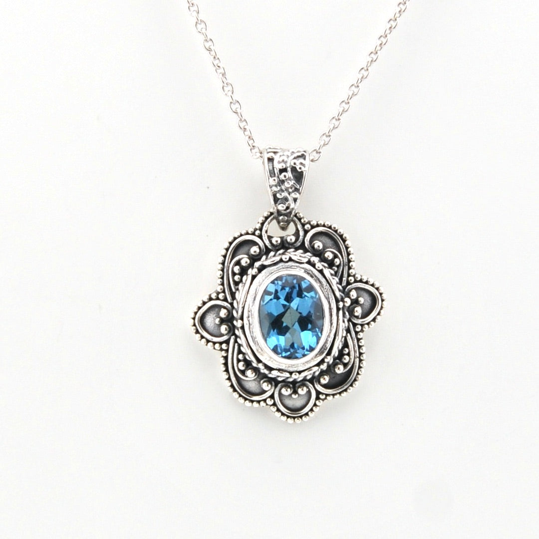 Silver pendant with blue gemstone on a white background