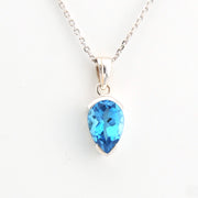 Teardrop-shaped blue gemstone pendant on a silver chain against a white background