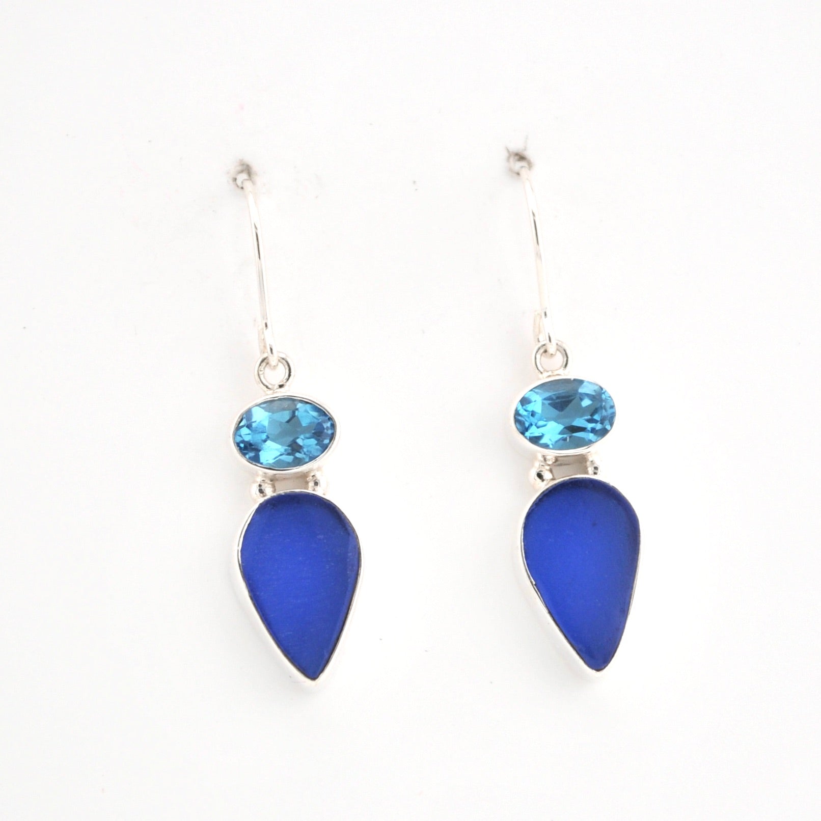 Pair of earrings with blue teardrop stones on a white background