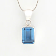 Silver pendant with a blue gemstone on a white background