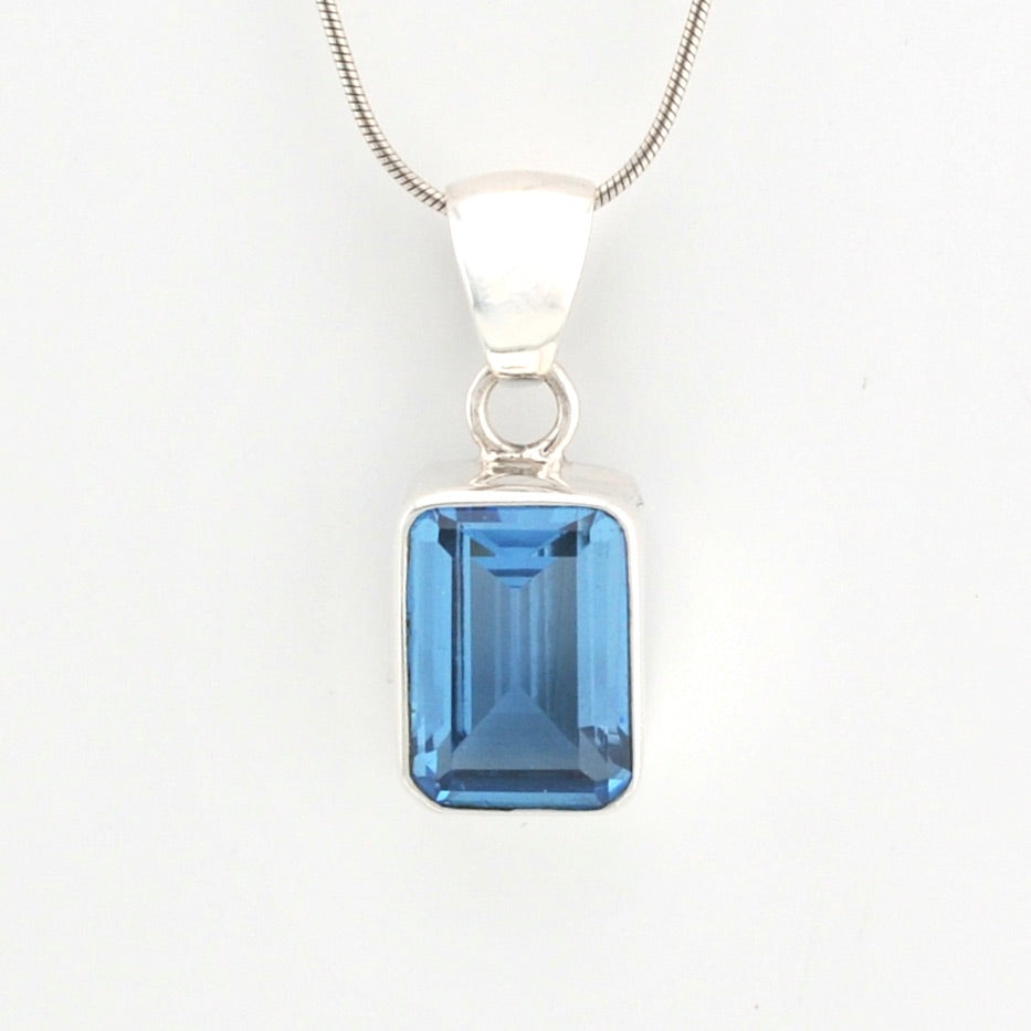Silver pendant with a blue gemstone on a white background