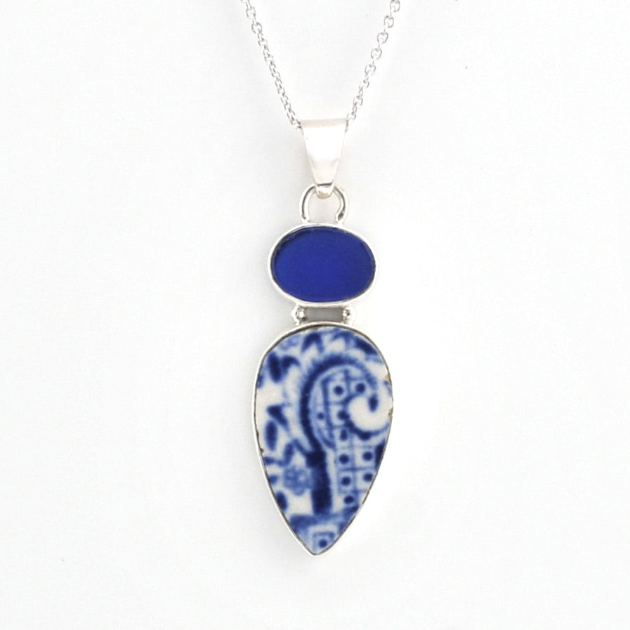 A silver pendant necklace featuring a teardrop-shaped blue and white patterned porcelain pendant and a smaller oval blue stone above it, on a white background.