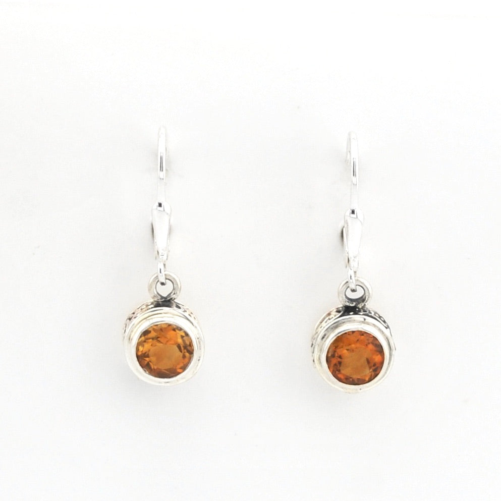 Pair of silver earrings with amber-colored gemstones on a white background