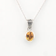 Silver pendant with a yellow gemstone on a white background