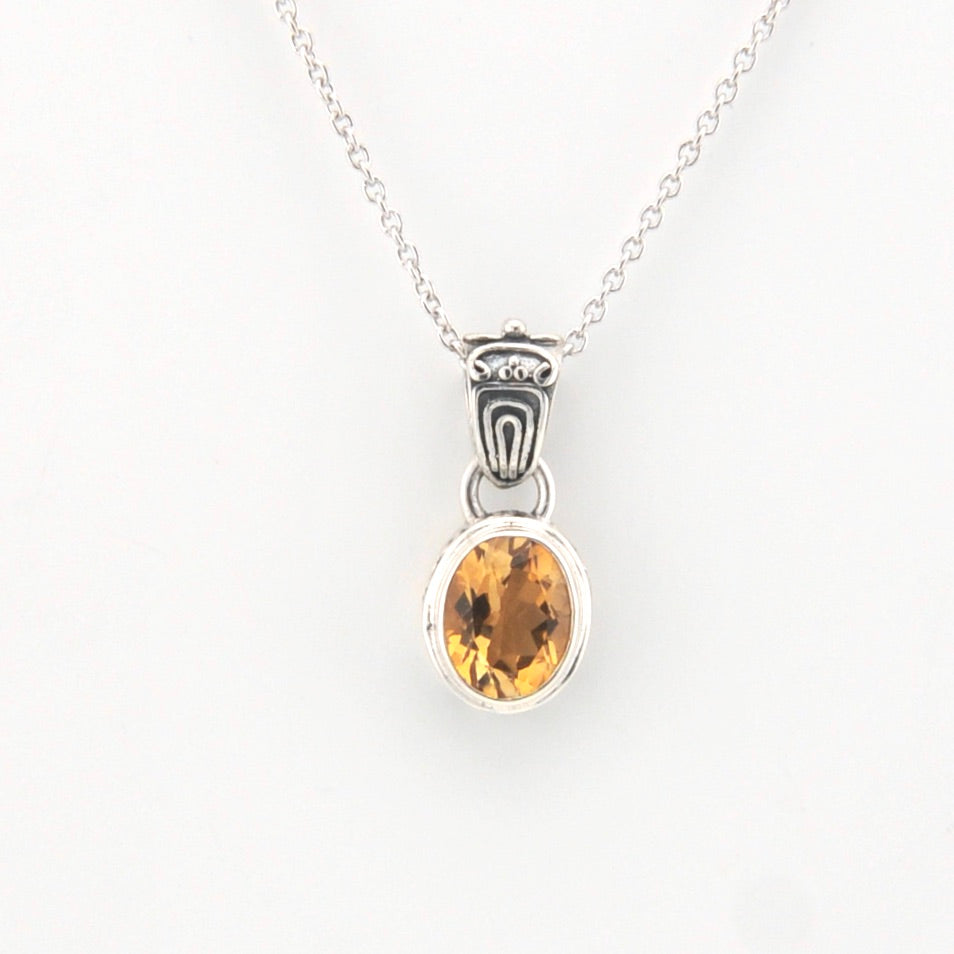 Silver pendant with a yellow gemstone on a white background