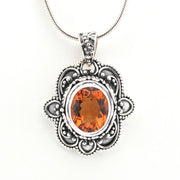 Silver pendant with an orange gemstone on a white background