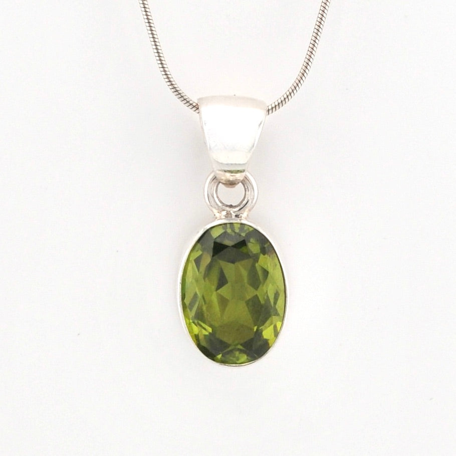 Green gemstone pendant on a silver chain against a white background
