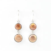 Pair of earrings with round beige stones on a white background