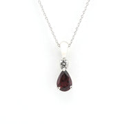 A silver pendant necklace featuring a teardrop-shaped dark red gemstone, suspended from a delicate silver chain against a plain white background.