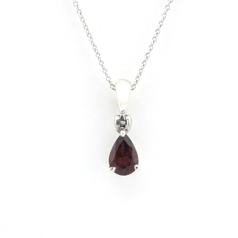 A silver pendant necklace featuring a teardrop-shaped dark red gemstone, suspended from a delicate silver chain against a plain white background.