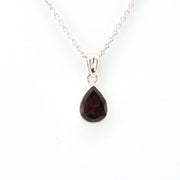Teardrop-shaped gemstone pendant on a silver chain against a white background