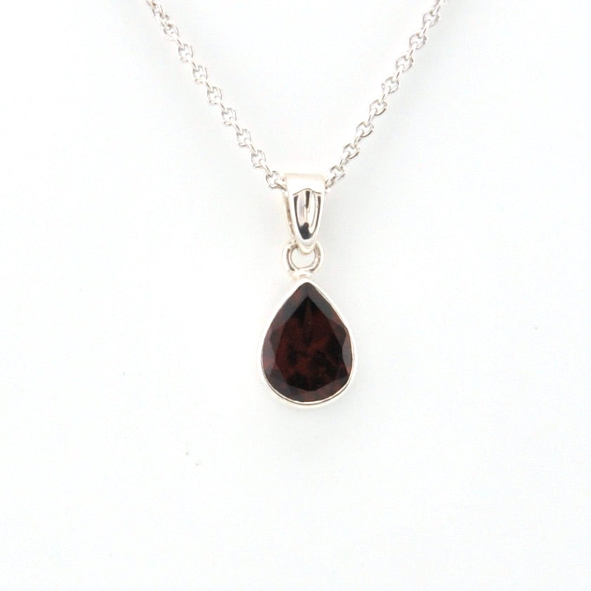 Teardrop-shaped gemstone pendant on a silver chain against a white background