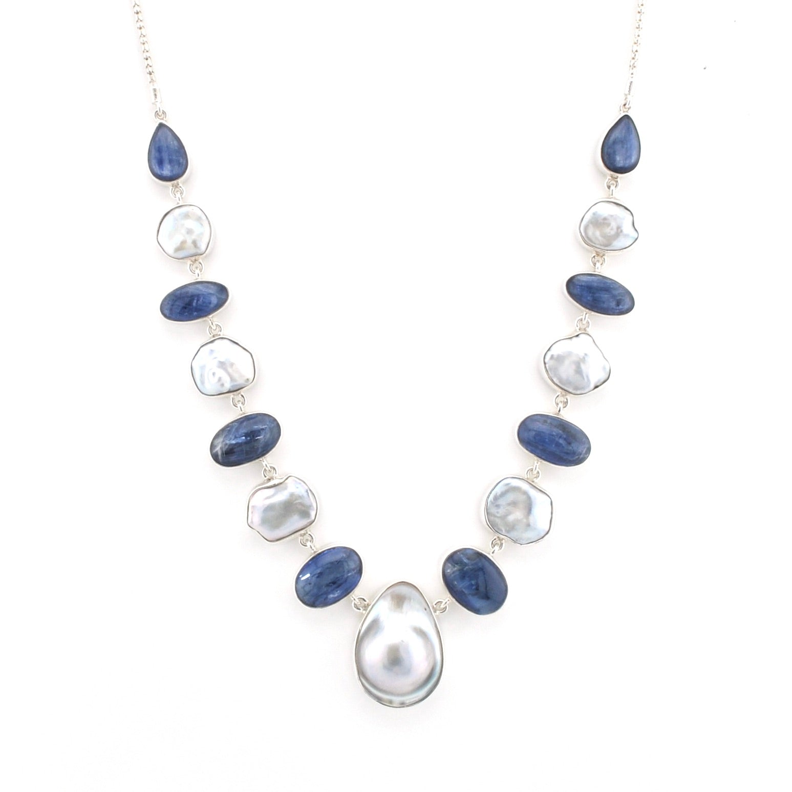 A silver-tone necklace featuring alternating polished dark blue oval stones and irregular white keshi pearls, with a large teardrop pearl pendant at the center, shown on a plain white background.