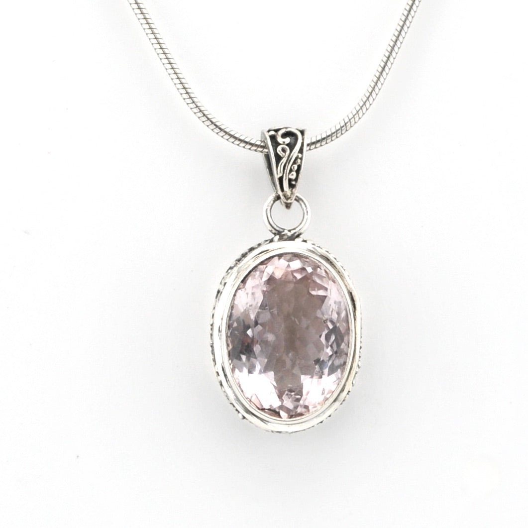Silver pendant with a pink gemstone on a white background
