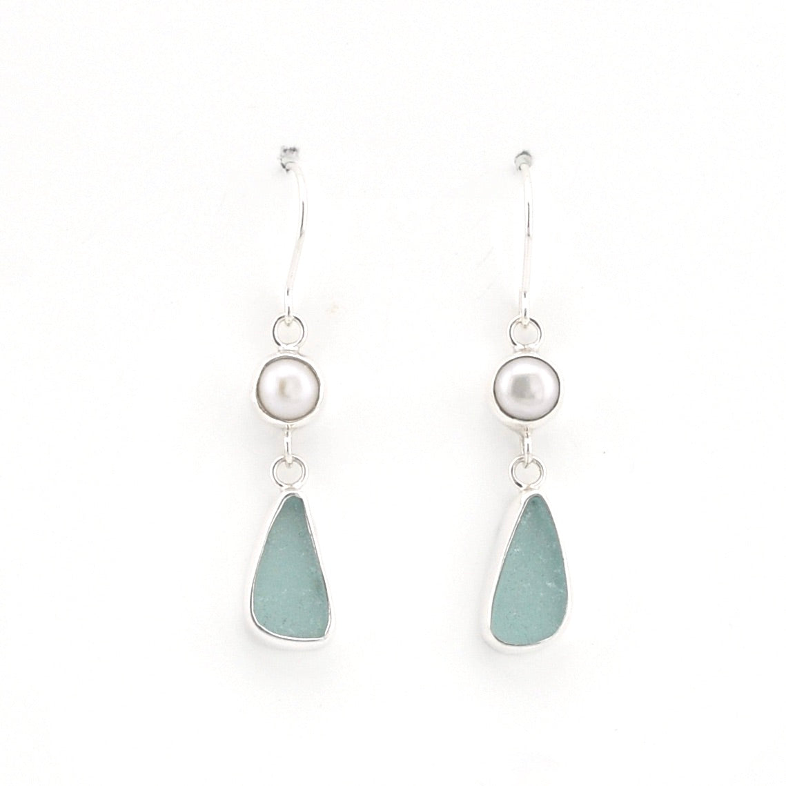 A pair of silver drop earrings featuring a small white pearl bead and a teardrop-shaped sea glass drop in a light blue-green color, set against a plain white background.