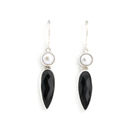 Pair of earrings with black teardrop-shaped stones and pearl-like centers on a white background