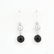 Pair of earrings with black stones and pearls on a white background