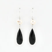 Pair of earrings with black teardrop-shaped stones and pearl-like tops on a white background