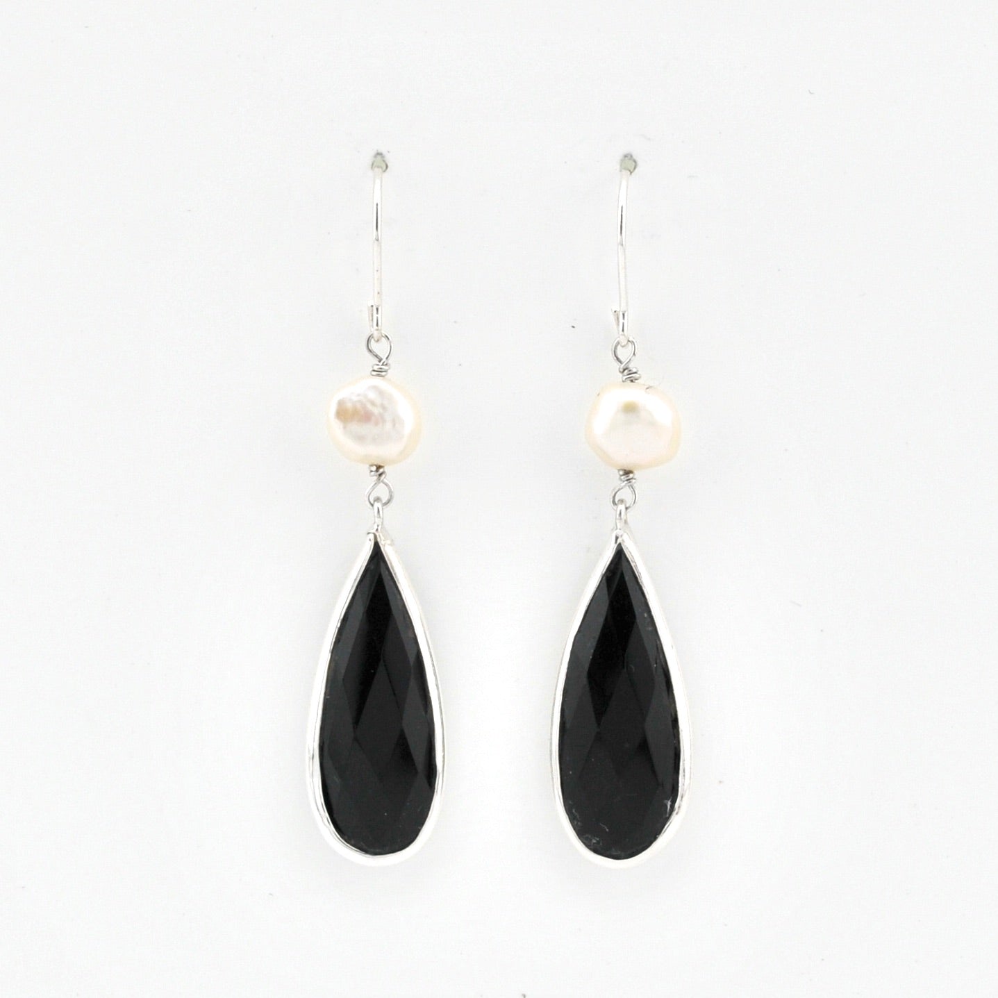 Pair of earrings with black teardrop-shaped stones and pearl-like tops on a white background