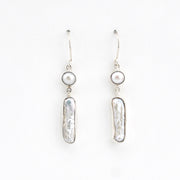 Pair of silver earrings with pearl-like beads on a white background