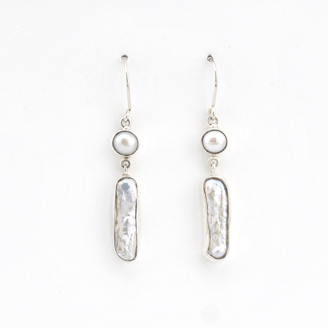 Pair of silver earrings with pearl-like beads on a white background