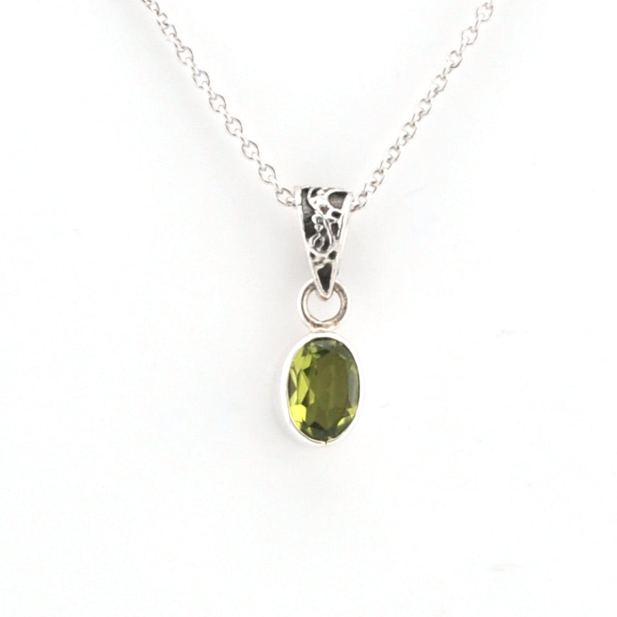 Green gemstone pendant on a silver chain against a white background