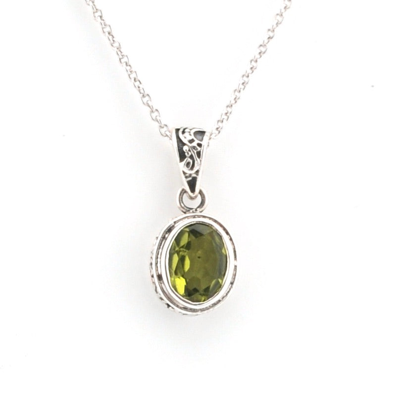 Silver pendant with a green gemstone on a white background