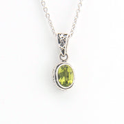 Silver pendant with a green gemstone on a white background