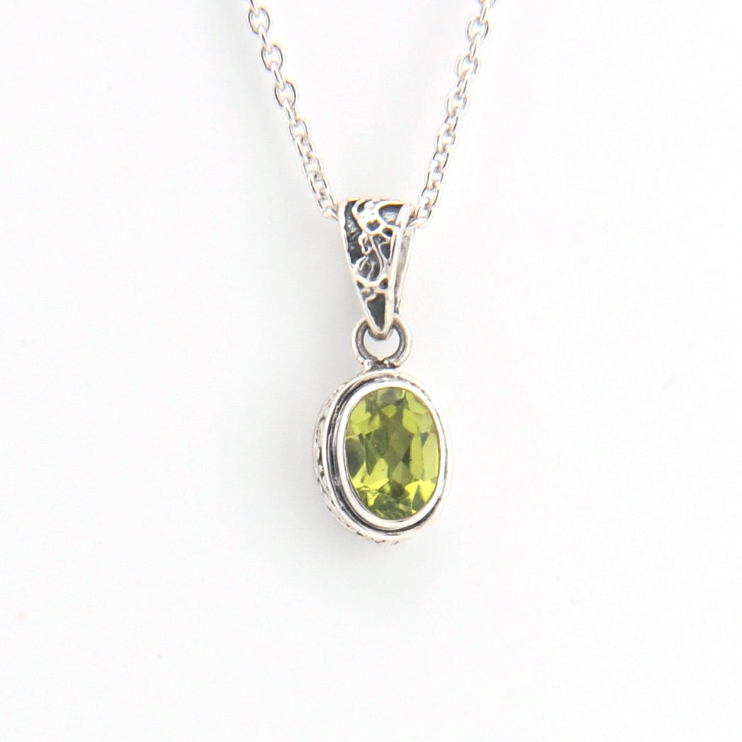 Silver pendant with a green gemstone on a white background