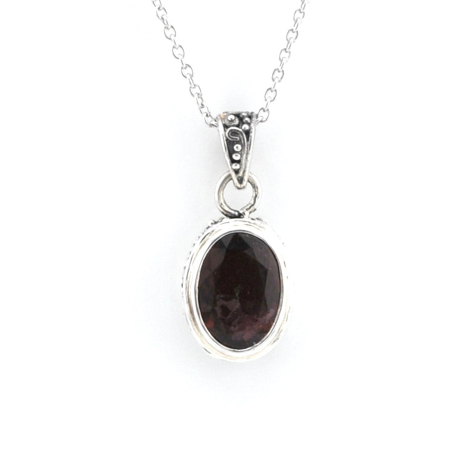 A silver pendant necklace featuring an oval dark brown gemstone in a textured silver bezel setting, suspended from a delicate silver chain against a plain white background.