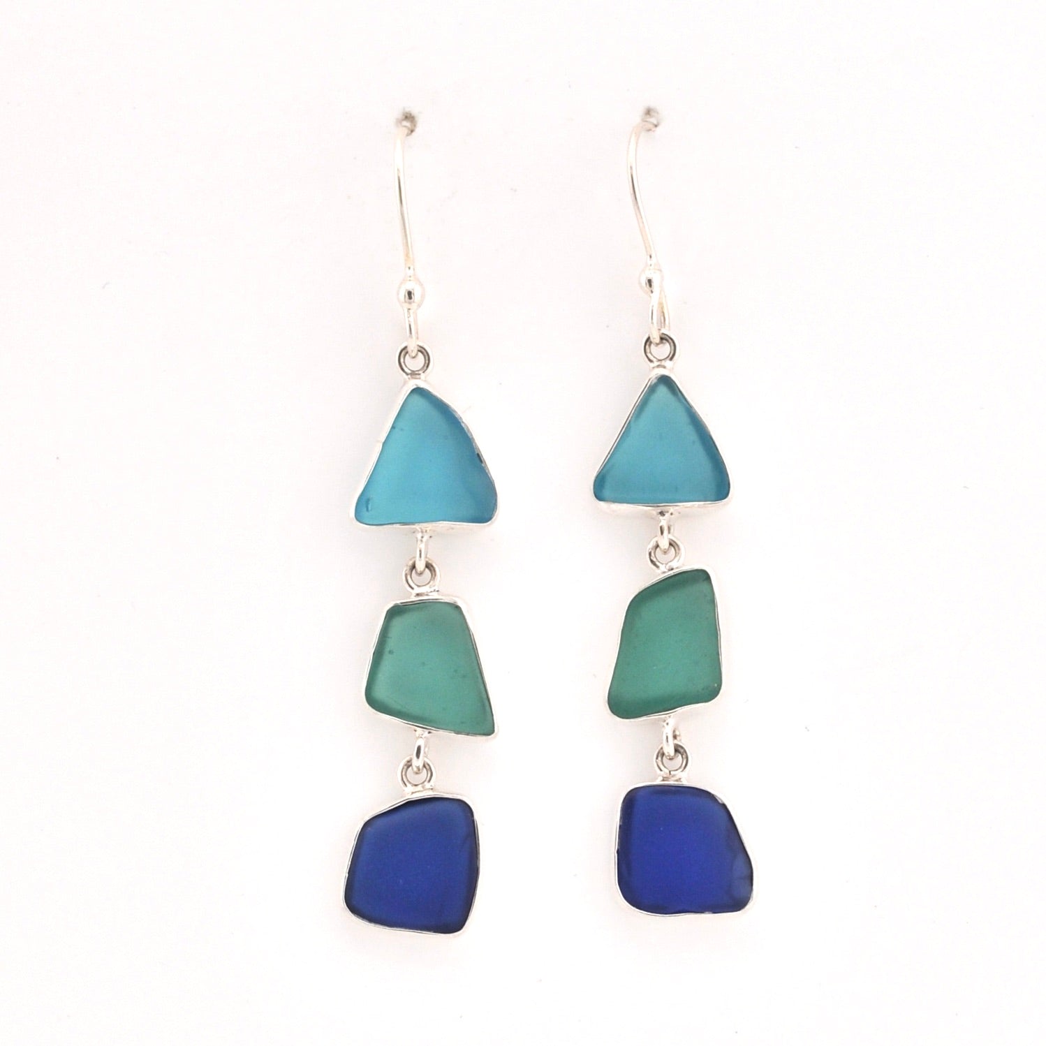 Pair of earrings with blue and green triangular glass on a white background