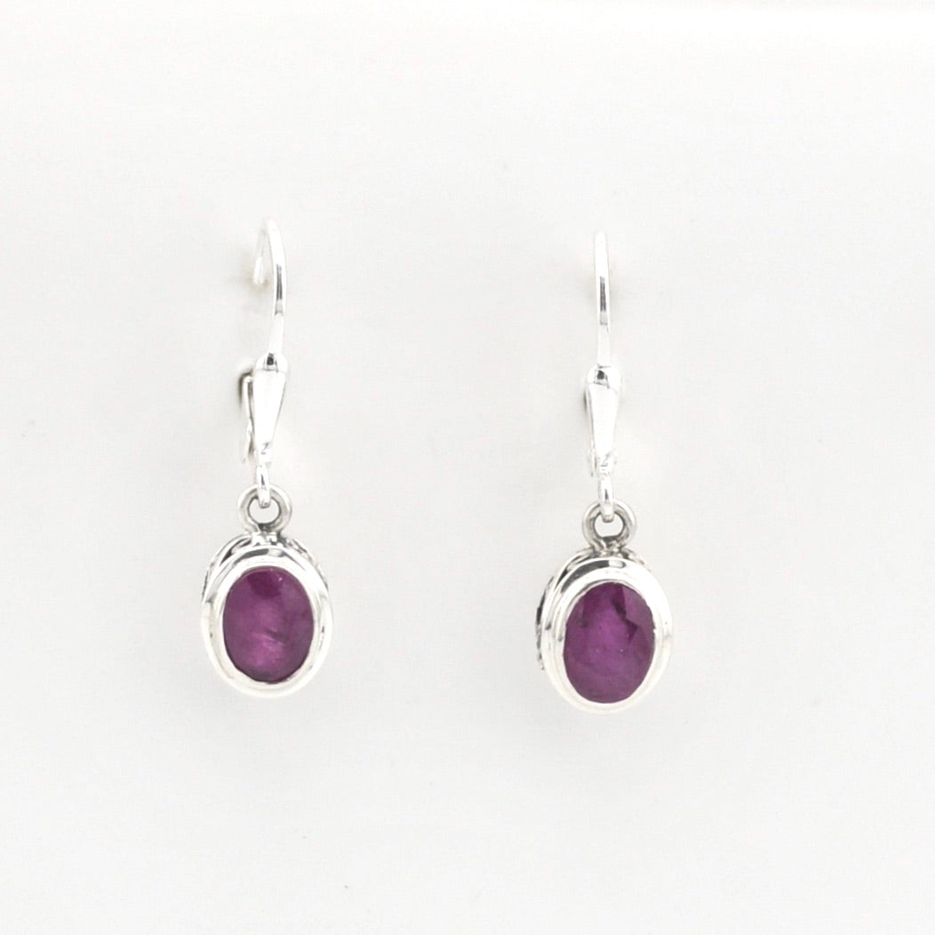 Pair of silver earrings with purple gemstones on a white background