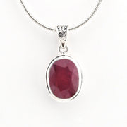 Ruby pendant on a silver chain against a white background