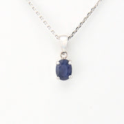Sapphire pendant on a silver chain against a white background