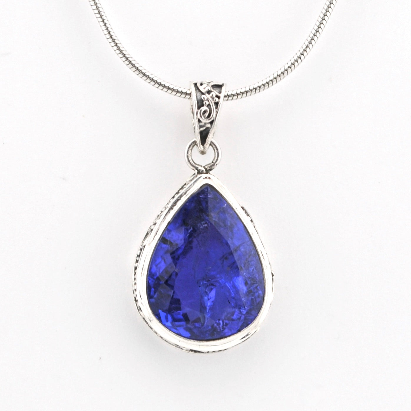 Teardrop-shaped blue gemstone pendant on a white background