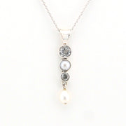 Necklace with three pearls and two gemstones on a white background