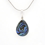 A silver teardrop pendant necklace featuring a natural iridescent abalone shell with blue, green, and black swirls, suspended from a silver snake chain against a white background.