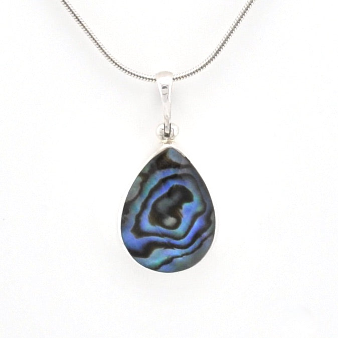 A silver teardrop pendant necklace featuring a natural iridescent abalone shell with blue, green, and black swirls, suspended from a silver snake chain against a white background.