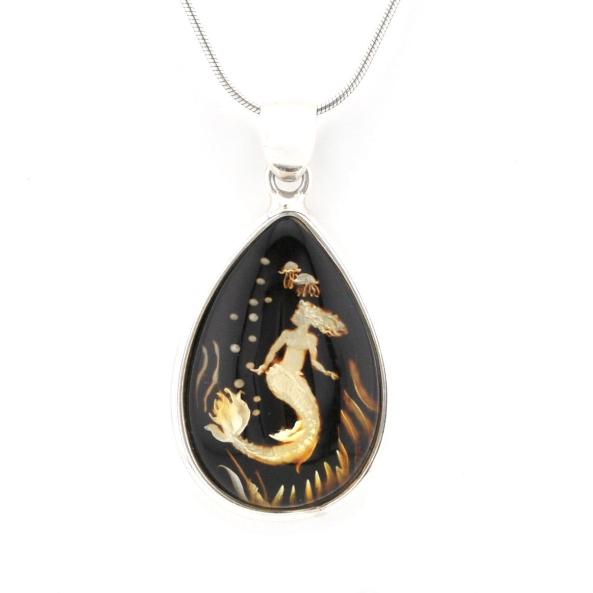 A teardrop-shaped pendant necklace featuring a mermaid design in gold over a black background, suspended from a silver-toned chain on a white background.