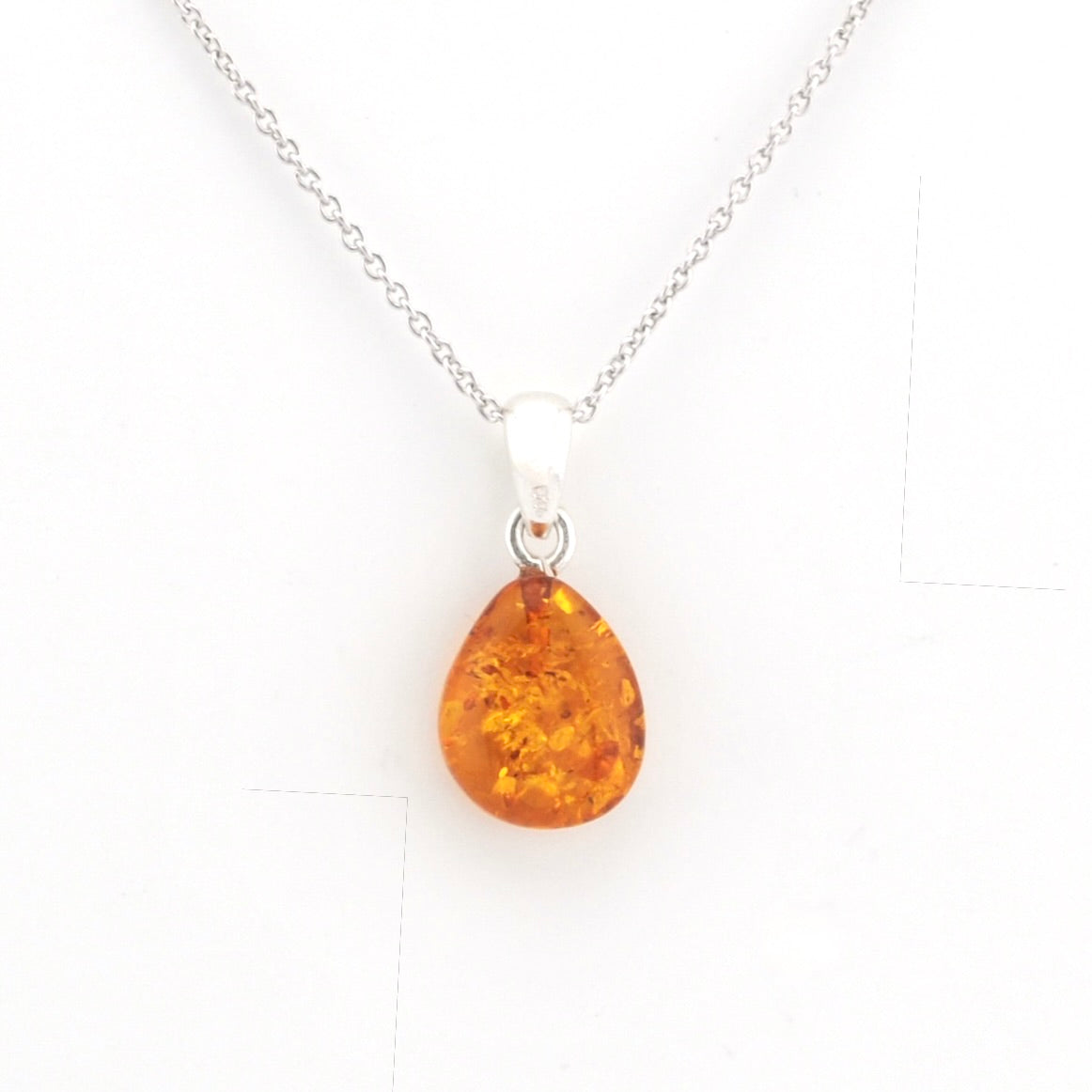 A teardrop-shaped amber pendant necklace on a delicate silver chain, displayed against a clean white background.