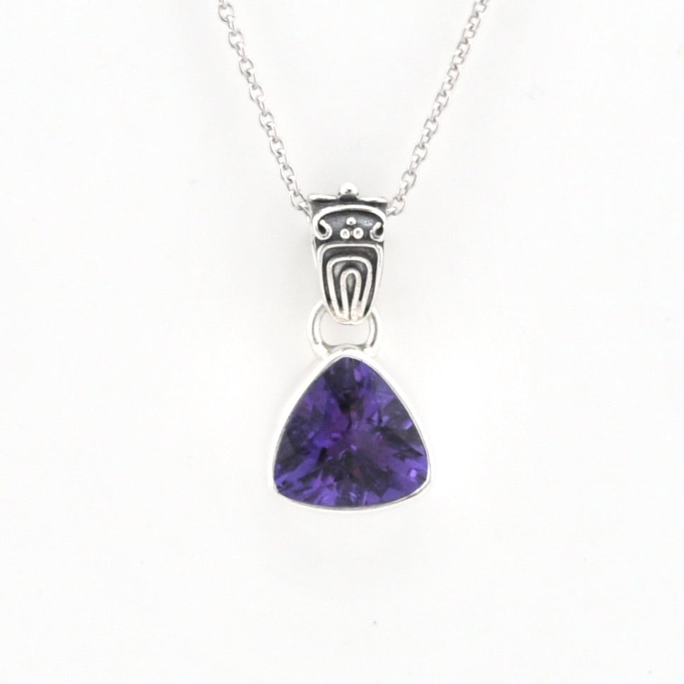 A silver pendant necklace featuring a triangular purple gemstone in a bezel setting, suspended from a delicate silver chain against a plain white background.