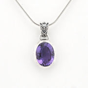 An oval purple amethyst pendant necklace in a silver bezel setting on a silver snake chain, shown against a plain white background.