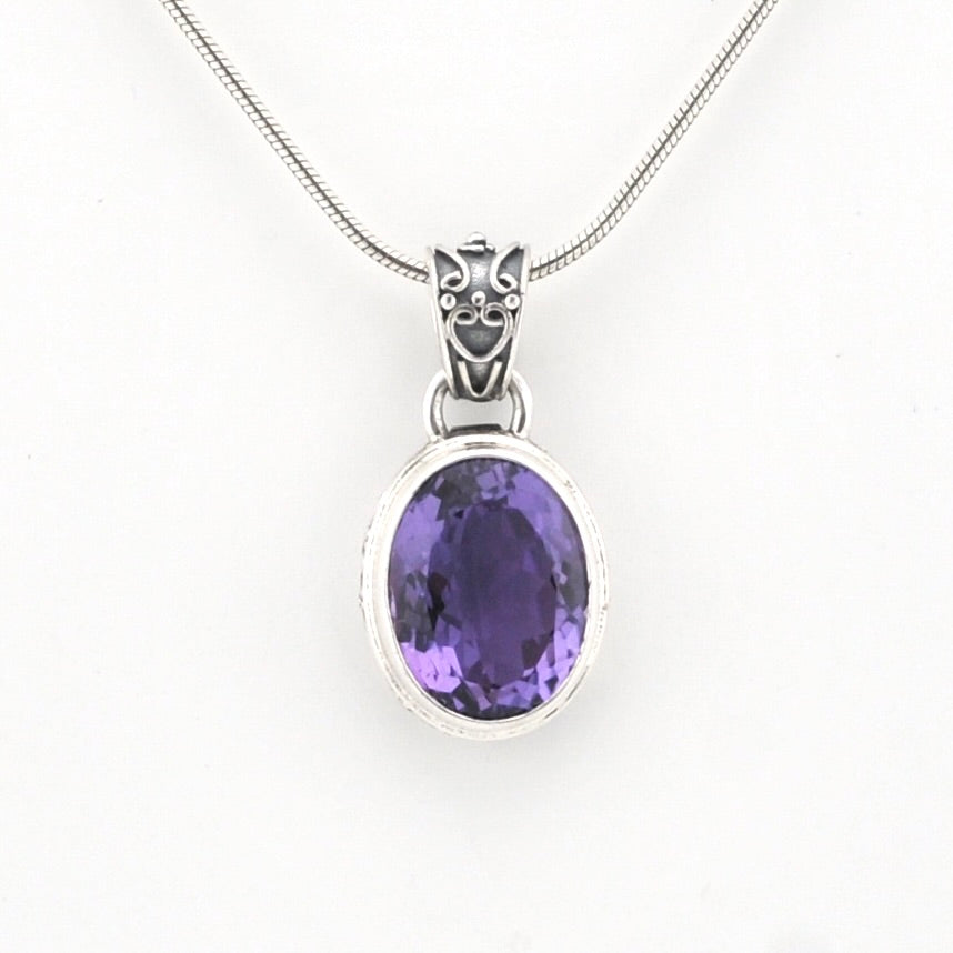 An oval purple amethyst pendant necklace in a silver bezel setting on a silver snake chain, shown against a plain white background.