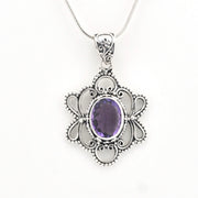 A silver filigree pendant necklace featuring an oval purple amethyst gemstone in the center, suspended from a delicate silver snake chain against a plain white background.