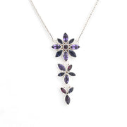 A silver-toned dangle necklace featuring a vertical arrangement of flower and leaf motifs set with dark purple marquise-cut gemstones, shown against a plain white background.