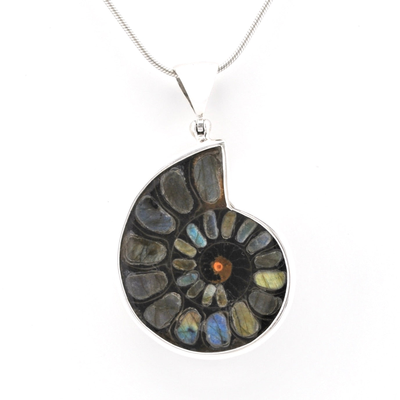 A silver pendant necklace featuring a spiral arrangement of polished labradorite stones and a central ammolite shell segment with a small orange center, suspended on a silver chain against a white background.