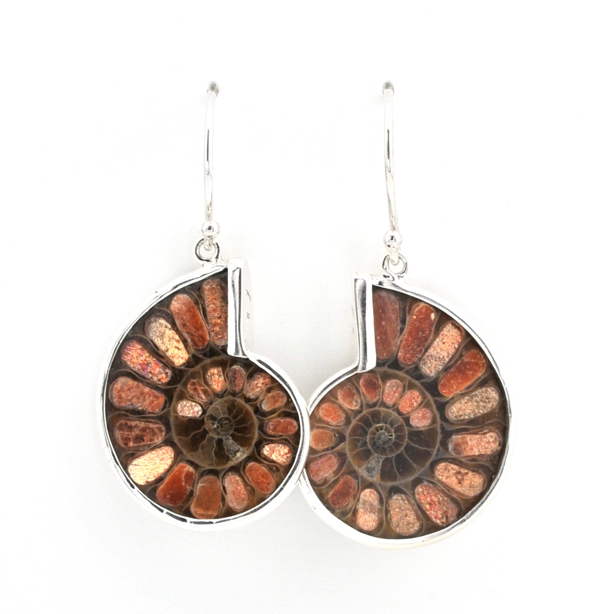 A pair of silver dangle earrings featuring circular inlay designs of brown and orange ammonite fossils, shown against a plain white background.